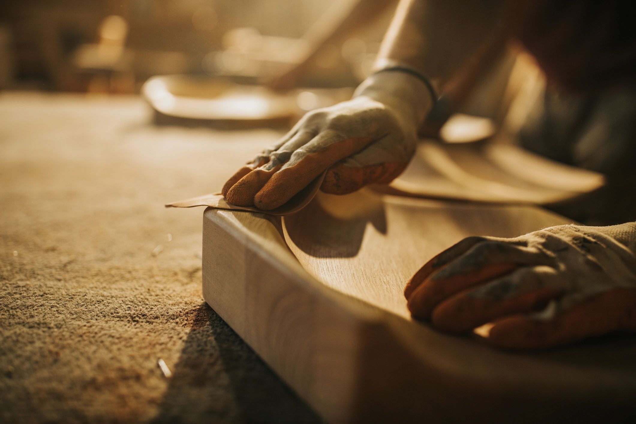 Hands sanding a piece of wood at a workbench